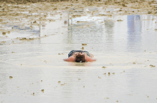 진흙탕이 된 미국 네바다주 버닝맨 축제 현장서 한 참가자가 누워 있는 모습. [로이터=연합뉴스]